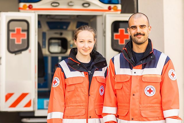 Zwei Mitarbeiter der Bereitschaften vor einem Rettungswagen