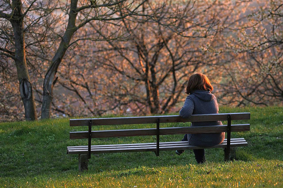 Einsame Mutter auf einer Parkbank im Winter